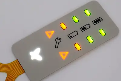 El mismo panel de membrana gris con indicadores verdes y ámbar y símbolos triangulares iluminados