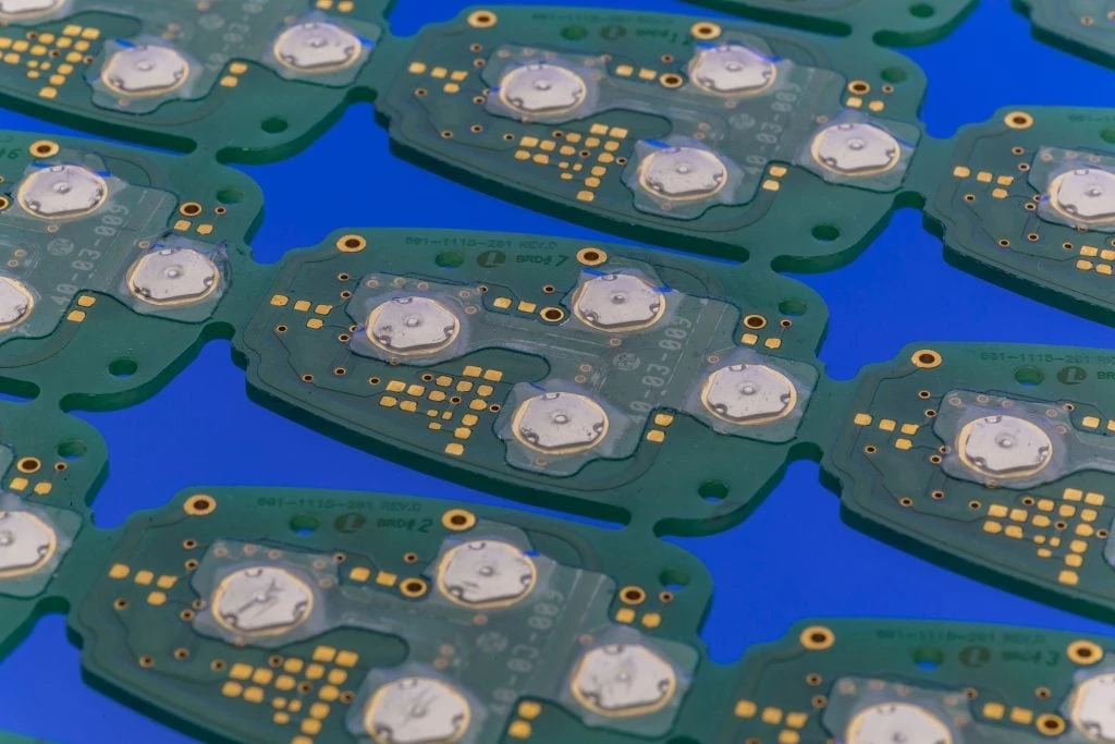 Dômes métalliques maintenus par un film transparent sur des circuits imprimés verts