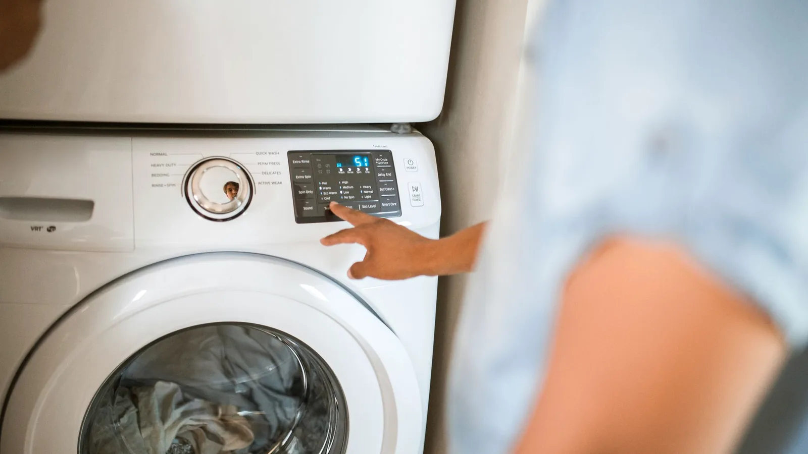 Person operating a washing machine control panel