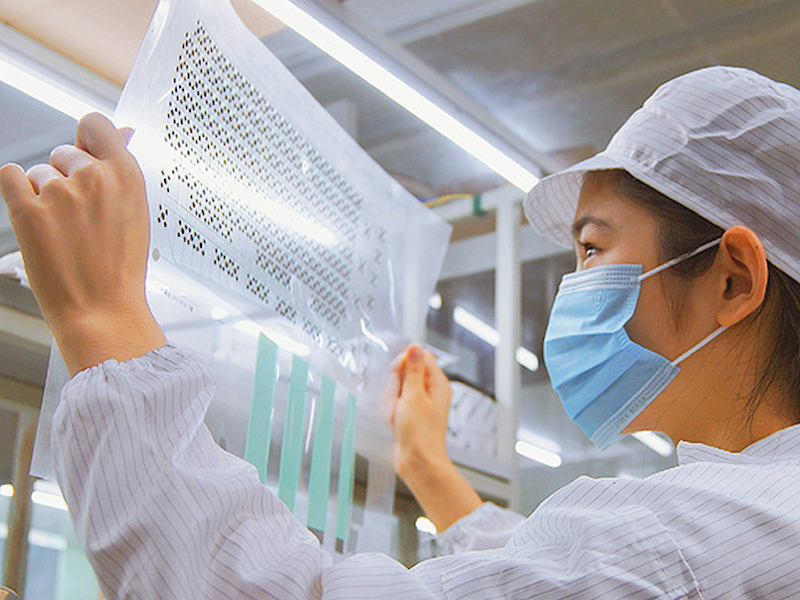 Opérateur d'usine effectuant le contrôle visuel d'un panneau à membrane