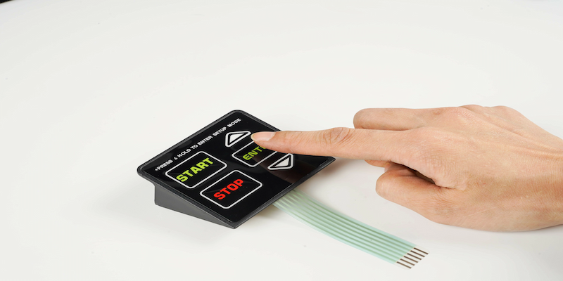 Opérateur appuyant sur un clavier à membrane avec touches START et STOP imprimées