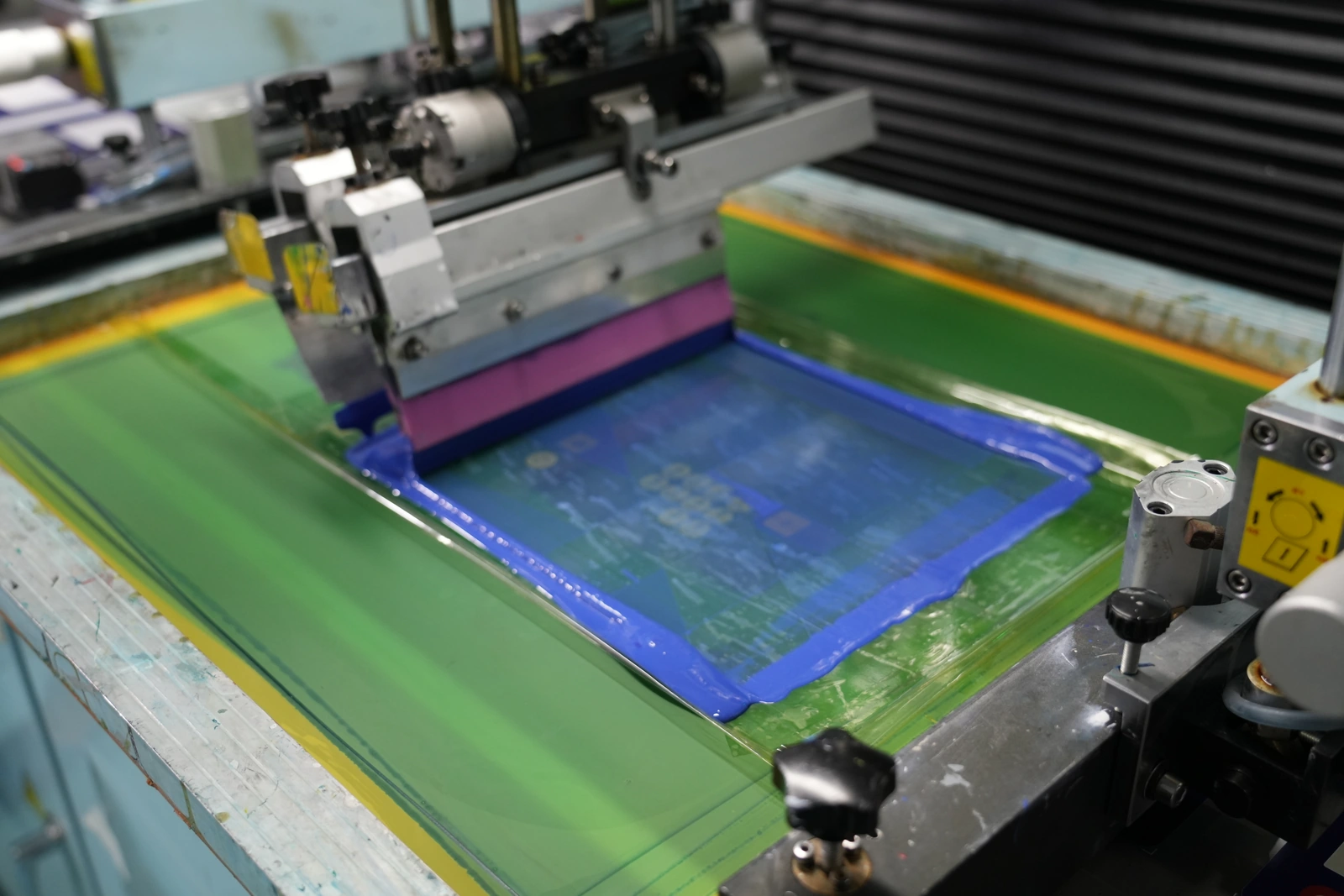 Screen-printing equipment with a squeegee and ink on a printing screen
