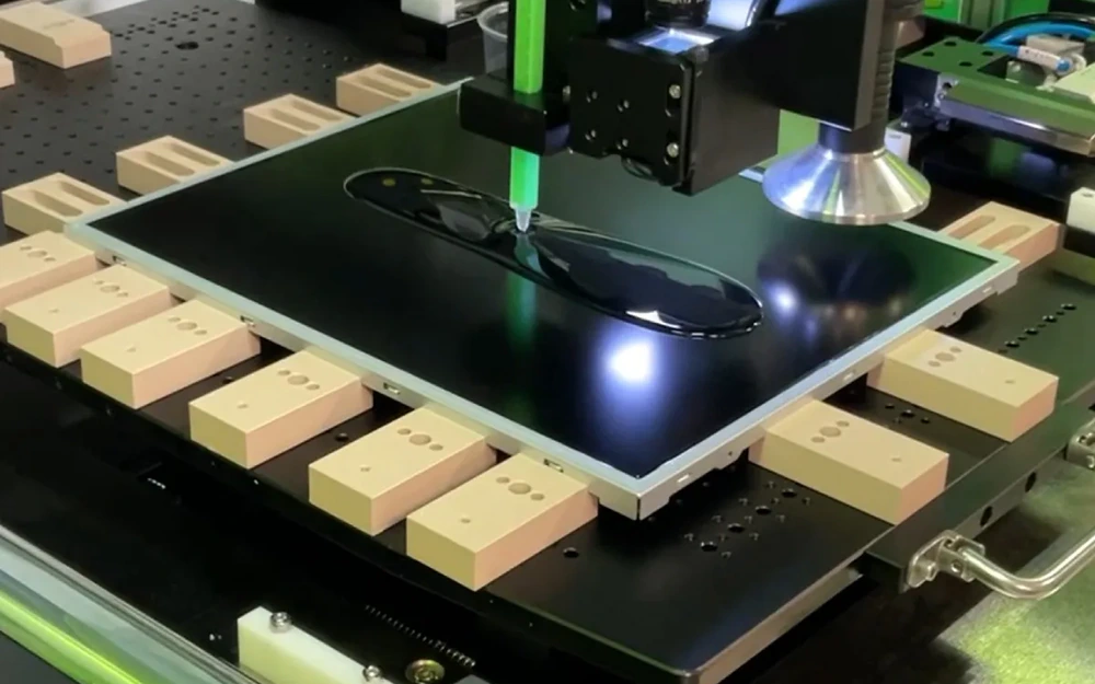 Real display module at an optical bonding workstation with clear bonding material on the front surface