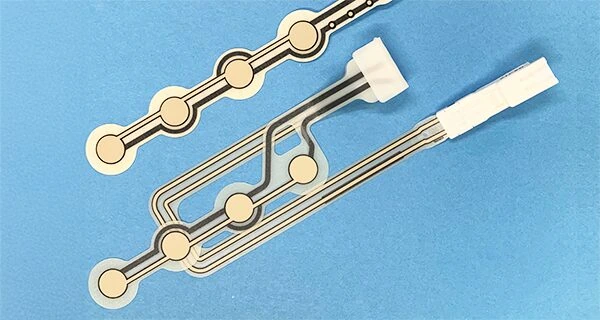 Two printed seat sensor layouts with circular sensing areas and different tail exits