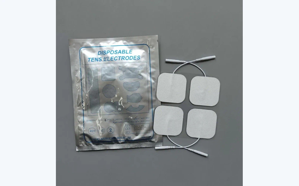 Quatre électrodes TENS et EMS à côté d’un sachet en aluminium imprimé