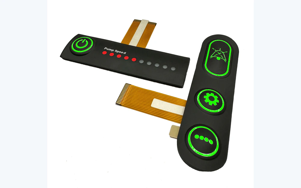 Two black silicone keypads with illuminated green legends and flexible circuit tails