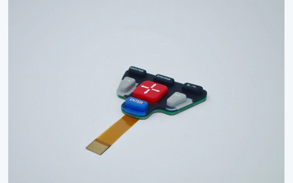 Raised keypad on a circuit board with a flat amber tail and exposed contact fingers