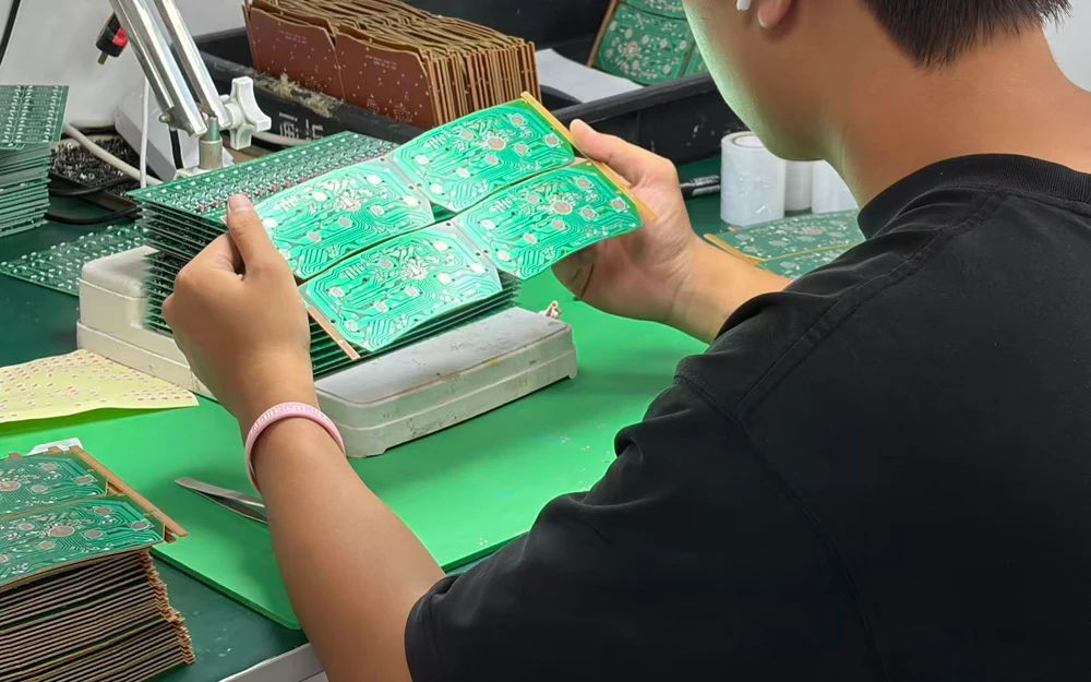 Worker visually inspecting a PCB panel during HMI assembly production
