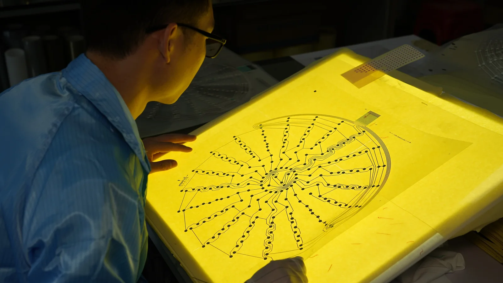 JASPER factory technician reviewing a printed membrane circuit on a light table